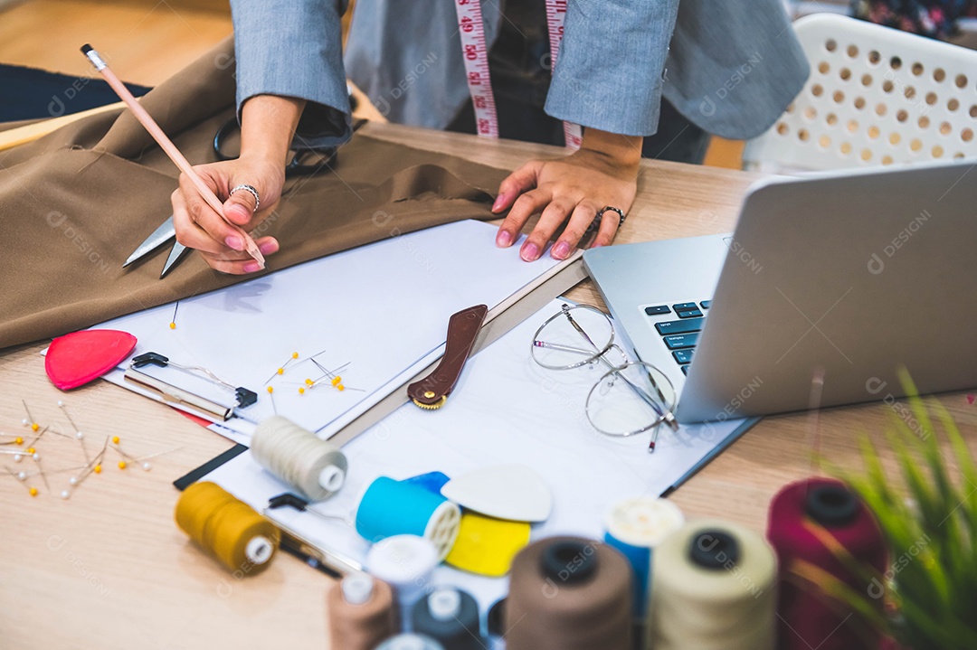 Close-up da mão de designer de moda feminina atraente trabalhando na oficina de escritório em casa.