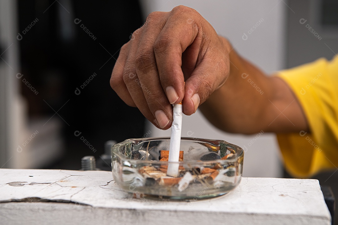 Mão apagando o cigarro e destruindo no cinzeiro ao ar livre na frente da casa. Conceito saudável e de pessoas. Tema do Dia Mundial Sem Tabaco.