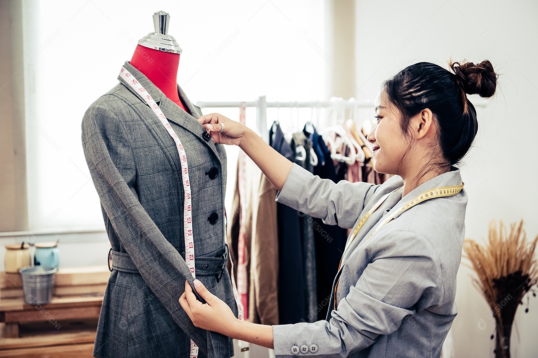 Menina estilista asiática fazendo ajuste no terno formal.