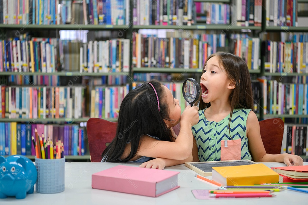 Duas garotinhas felizes fazendo careta e brincando juntas na biblioteca da escola como exame de saúde dental.