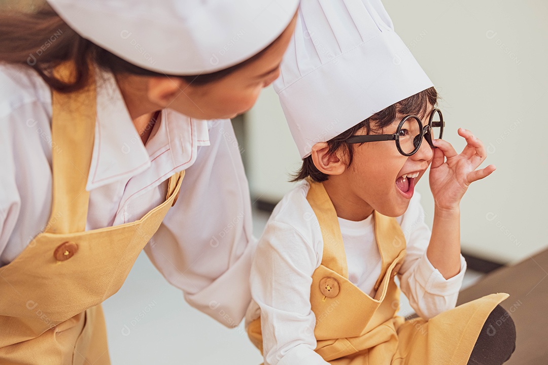 Menino bonito e feliz asiático interessado em cozinhar com a mãe.