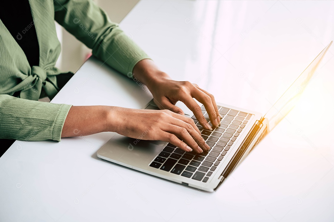 Detalhe da mão de uma mulher trabalhando no escritório doméstico e digitando no teclado.