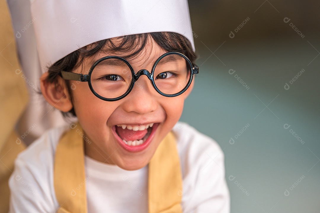 Retrato de um menino asiático bonito e feliz interessado em cozinhar.