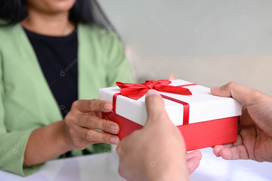 Closeup de mãos dando caixa de presente no dia de Natal e festival de ano novo para o outro com fundo de mulher.