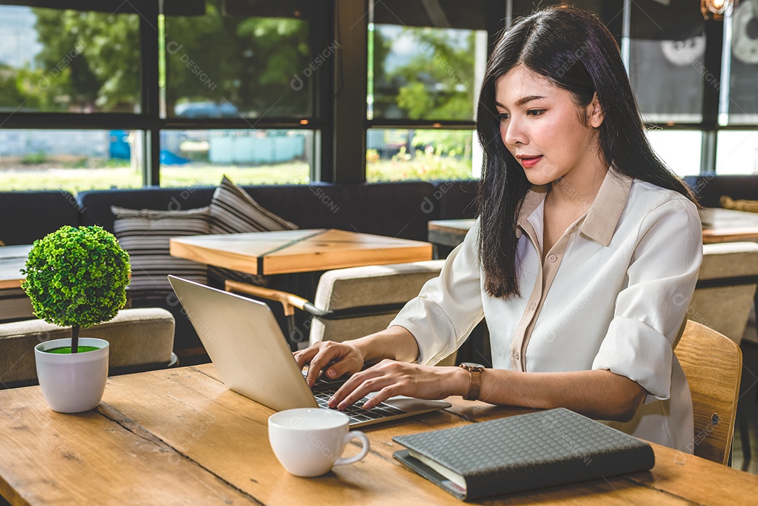 Mulher asiática trabalhando com laptop na cafeteria. Pessoas e Vidas.