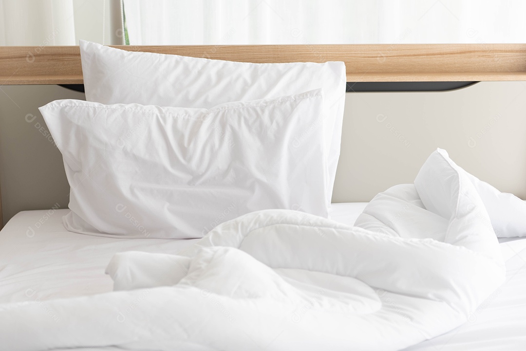 Cama desfeita branca pela manhã com luz do sol com cortina branca.