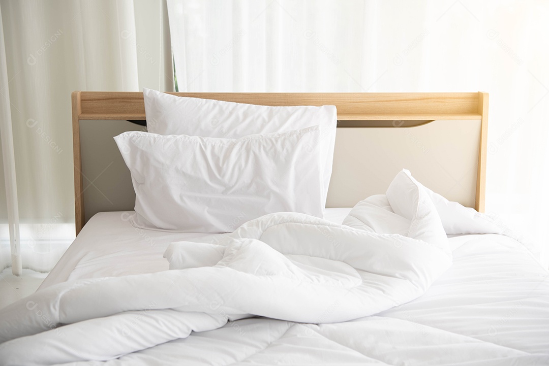 Cama desfeita branca pela manhã com luz do sol com cortina branca.