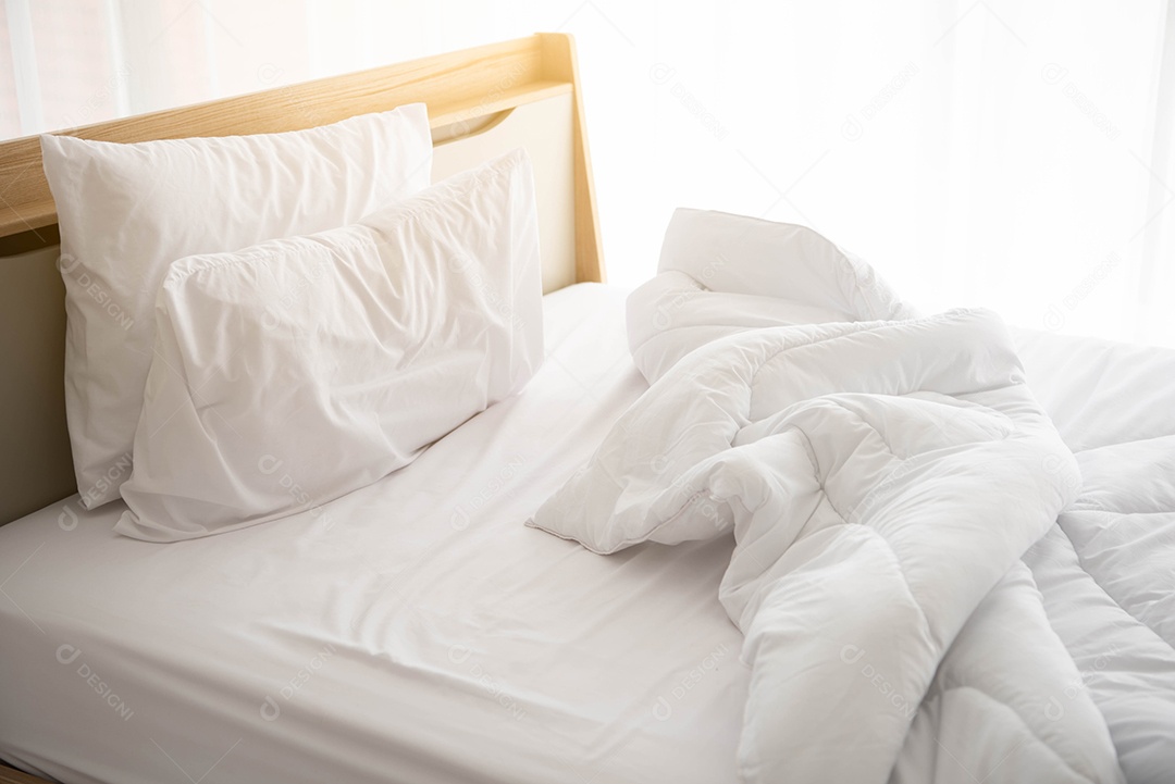 Cama desfeita branca pela manhã com luz do sol com cortina branca.