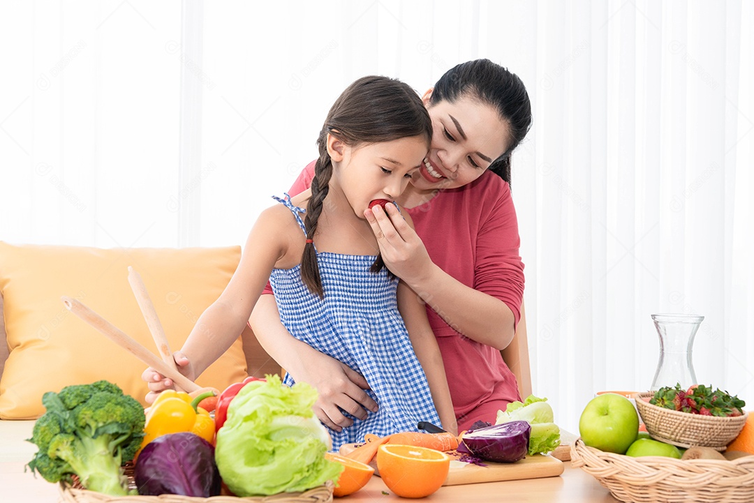 Mãe e filha cozinhando e comendo comida caseira juntas.