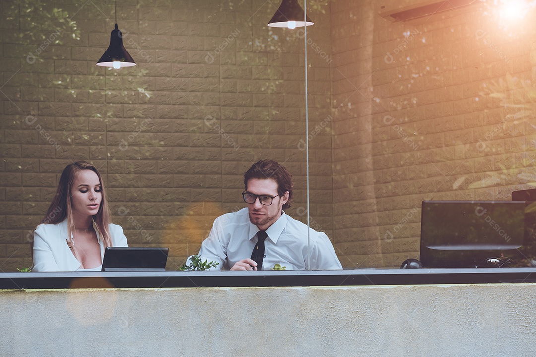 Dois homens e mulheres trabalham juntos em um escritório claro com árvore.