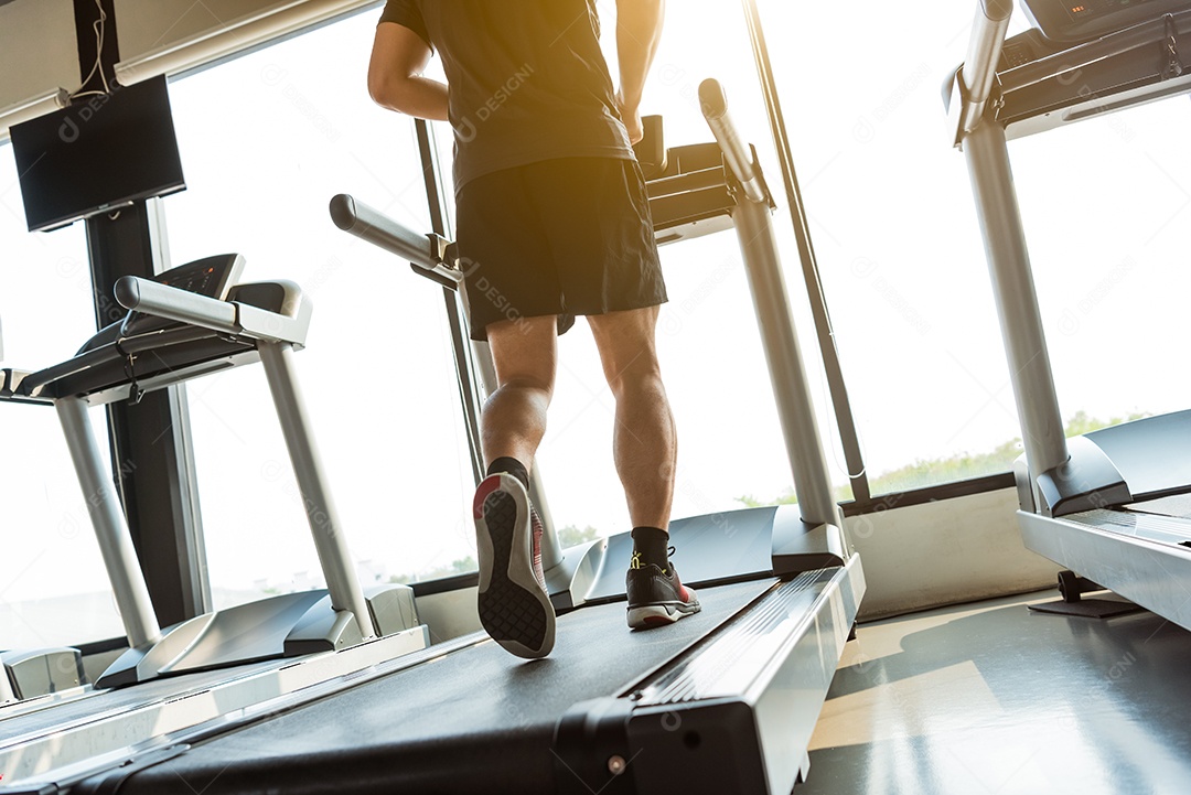 Pernas do esportista correndo na esteira no ginásio de fitness.