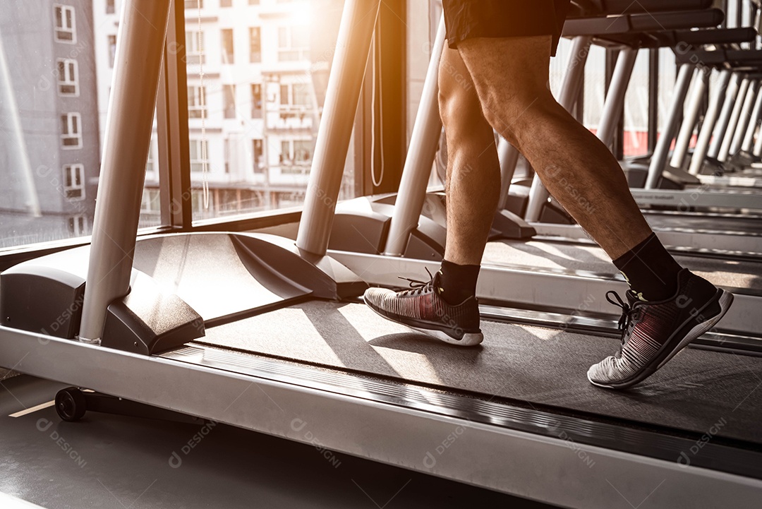 Feche acima do homem do esporte que corre na esteira no ginásio de fitness.