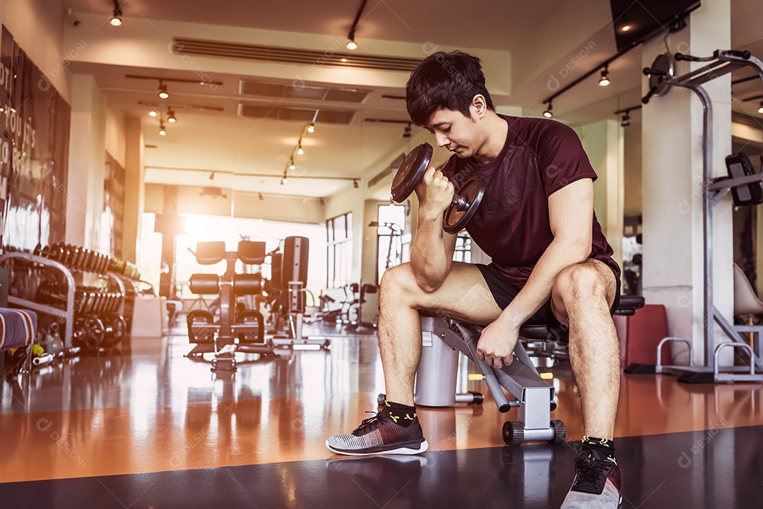 Homem do esporte asiático levantando halteres no banco de fitness com equipamento de ginástica.