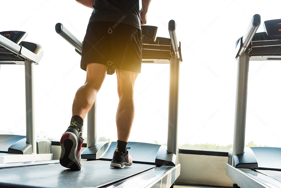 Sportsman's legs running on treadmill in fitness gym.