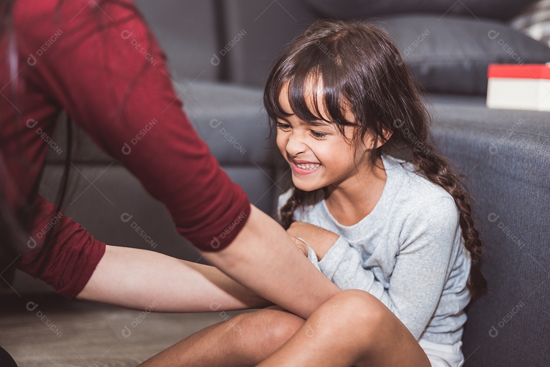 Menina caucasiana agradada pela mãe na sala de estar. Estilo de vida de pessoas e conceito de crianças.