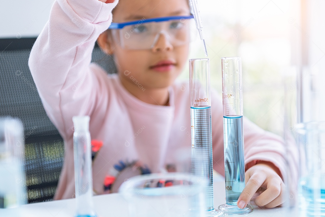 Menina asiática segurando e soltando solução azul na banheira de ensaio.