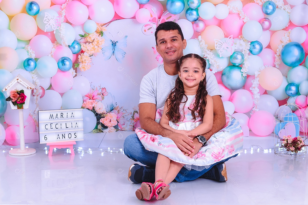 Lindos pai e filha sentada sobre o chão em cénario de aniversário