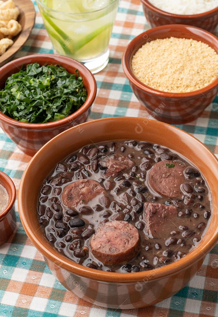 Feijoada típica brasileira com arroz, caipirinha, farofa e torresmo.