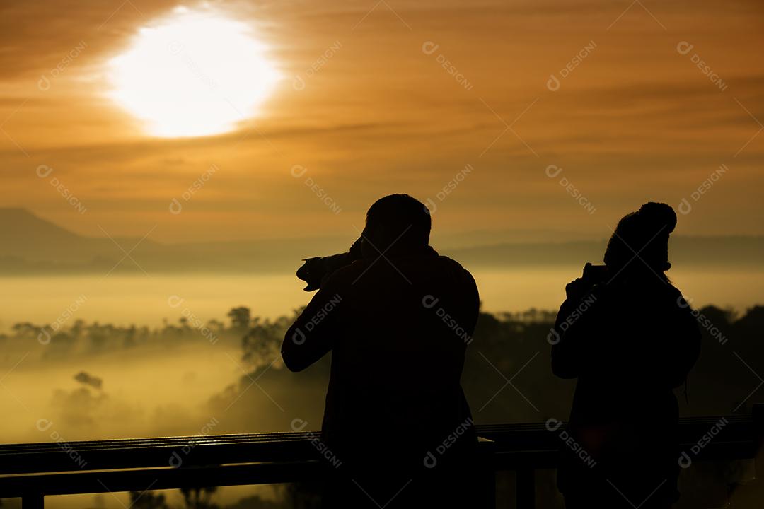 silhueta da fotografia asiática tire uma foto do belo nascer do sol dourado e nuvens nebulosas na floresta no Parque Nacional Thung Salaeng Luang, Tailândia