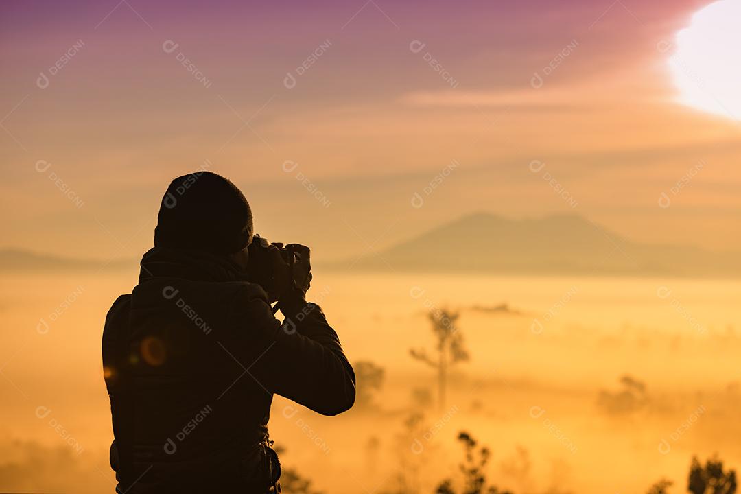 silhueta da fotografia asiática tire uma foto do belo nascer do sol dourado e nuvens nebulosas na floresta no Parque Nacional Thung Salaeng Luang, Tailândia