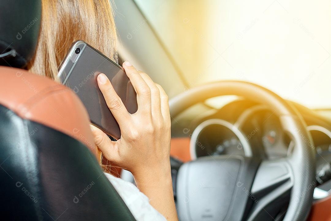 As mulheres asiáticas estão dirigindo carros e usando um smartphone na estrada.