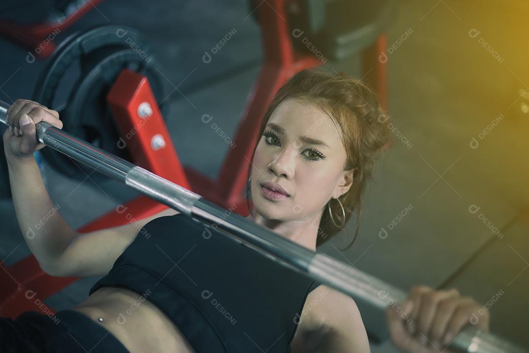 jovem fitness mulher asiática exercício com máquina Cable Crossover e levantamento de halteres e halteres no ginásio para construir músculos