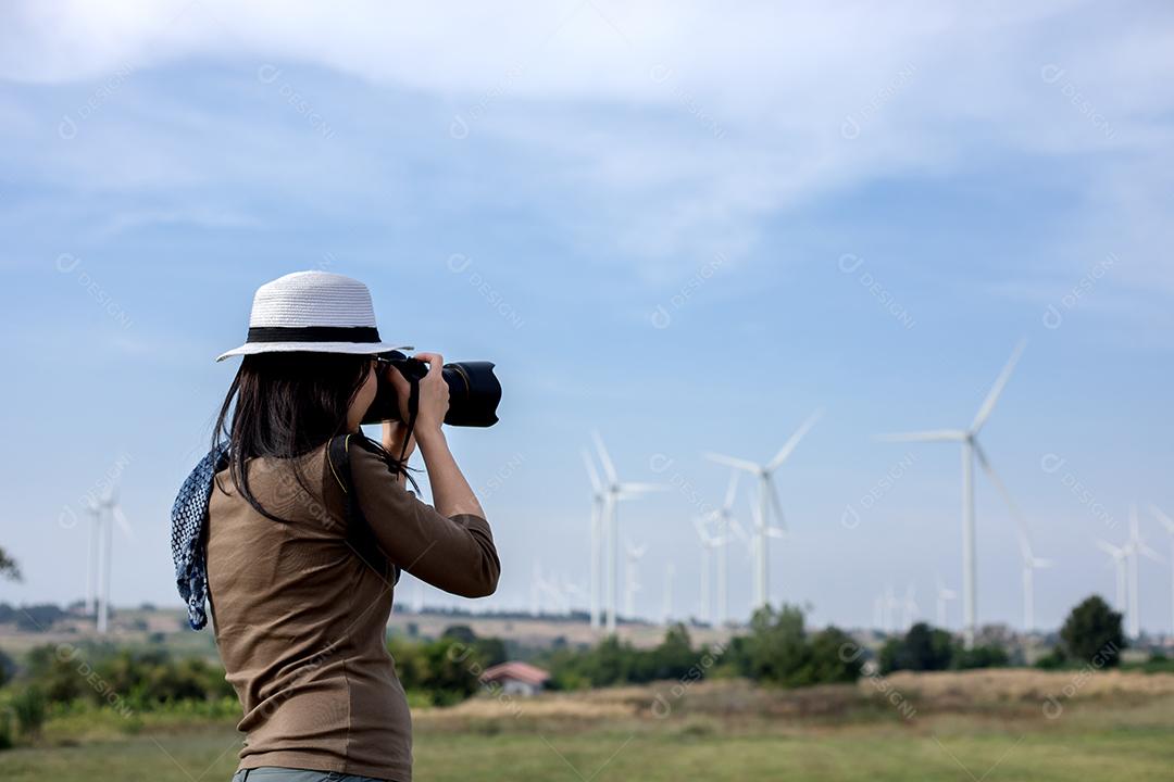 Fotógrafo de mulheres segurando uma câmera na turbina eólica para tirar uma foto.