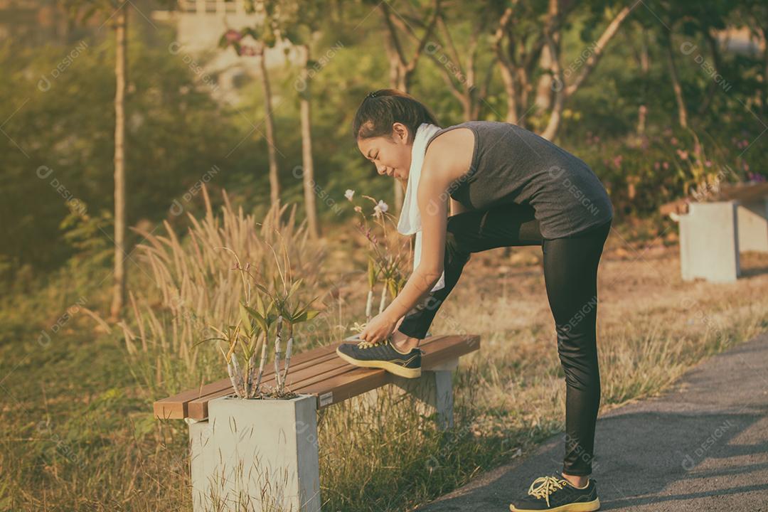 Desfocado de mulheres ásia esporte, fitness, exercício e conceito de estilo de vida - corredor mulher amarrando sapatos de treinador