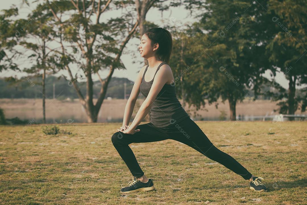 Asian athletic woman warming up and young athlete sitting on a workout and stretching in a park before jogging outdoors, healthy lifestyle concept, soft focus