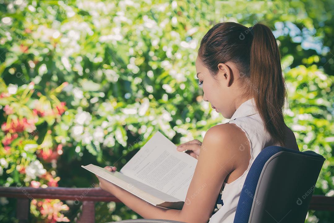 Mulher asiática lendo um livro no jardim para relaxar o tom vintage