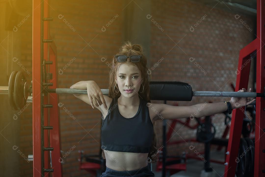jovem fitness mulher asiática exercício com máquina Cable Crossover e levantamento de halteres e halteres no ginásio para construir músculos