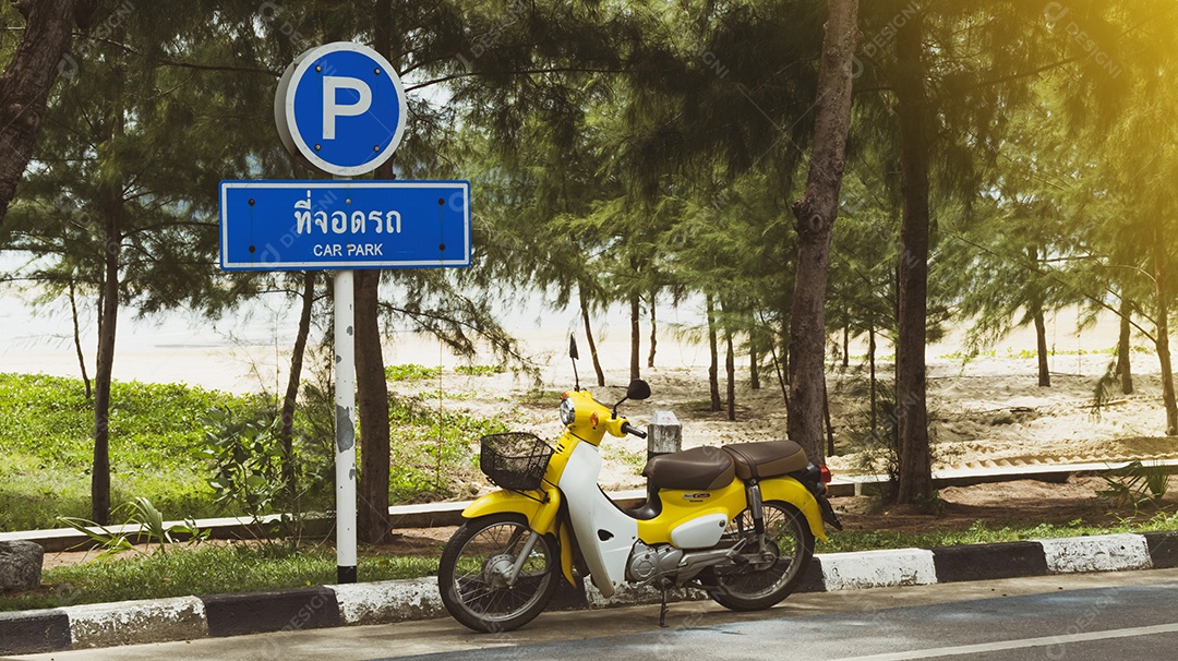 Uma motocicleta Honda amarela brilhante, Super cub, está estacionada ao lado de um sinal de trânsito designado como estacionamento.