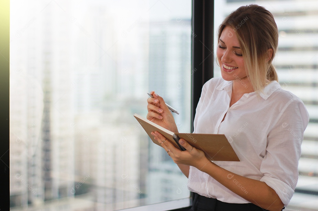 Retrato de uma empresária segurando um notebook no escritório moderno
