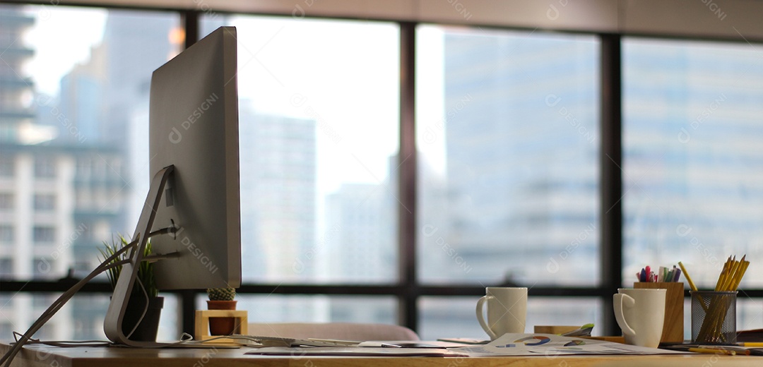 Escritório de mesa de mesa de madeira com tela de computador grande em janelas e fundo de construção