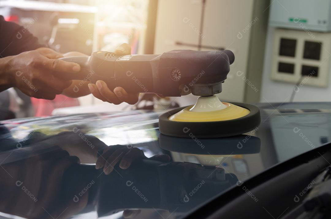 Homem segurando ferramenta polonês reparação de automóveis detalhando manutenção de arranhões de carro de capô no trabalho de lavagem de carros de garagem.