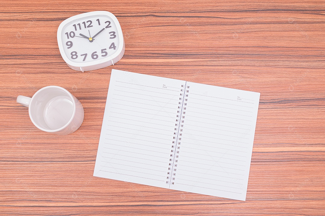 Caderno e o relógio estão sobre a mesa