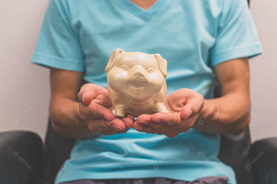 Mão segurando um cofrinho, conceito de economia de dinheiro