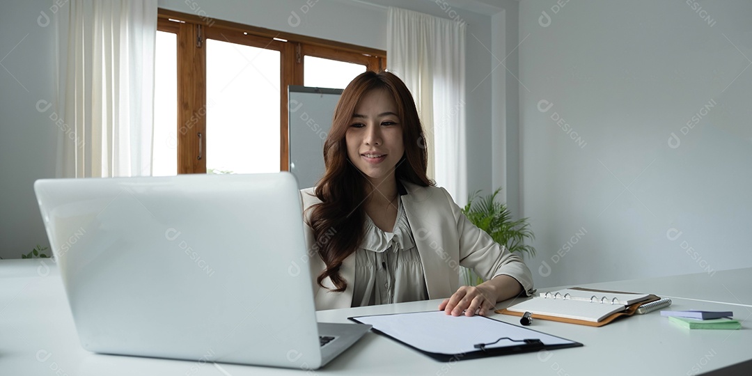 Bela jovem asiática sentada usando o laptop.