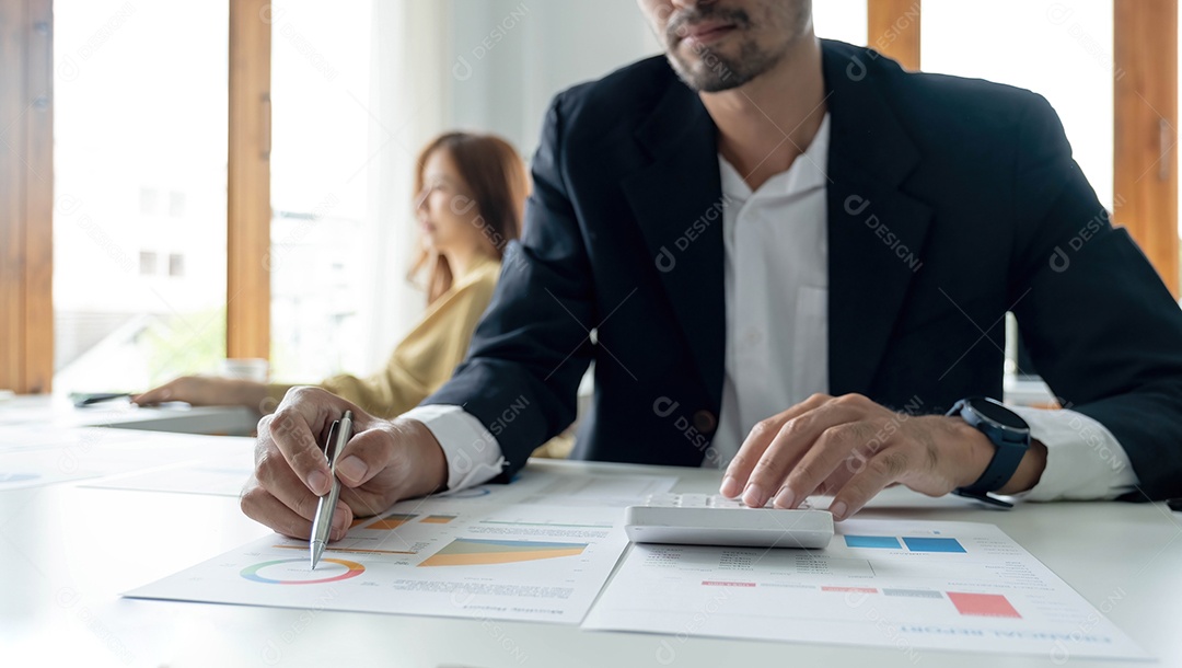 Homem de negócios apontando para papelada e usando computador portátil.