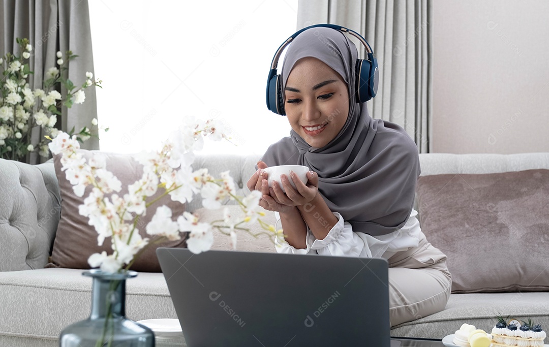 Estilo de vida doméstico. Mulher muçulmana feliz usando laptop em casa