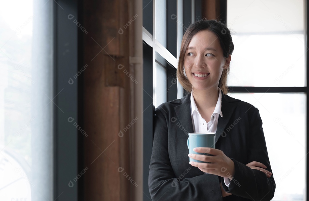 Sorrindo jovem empresária asiática segurando uma caneca de café