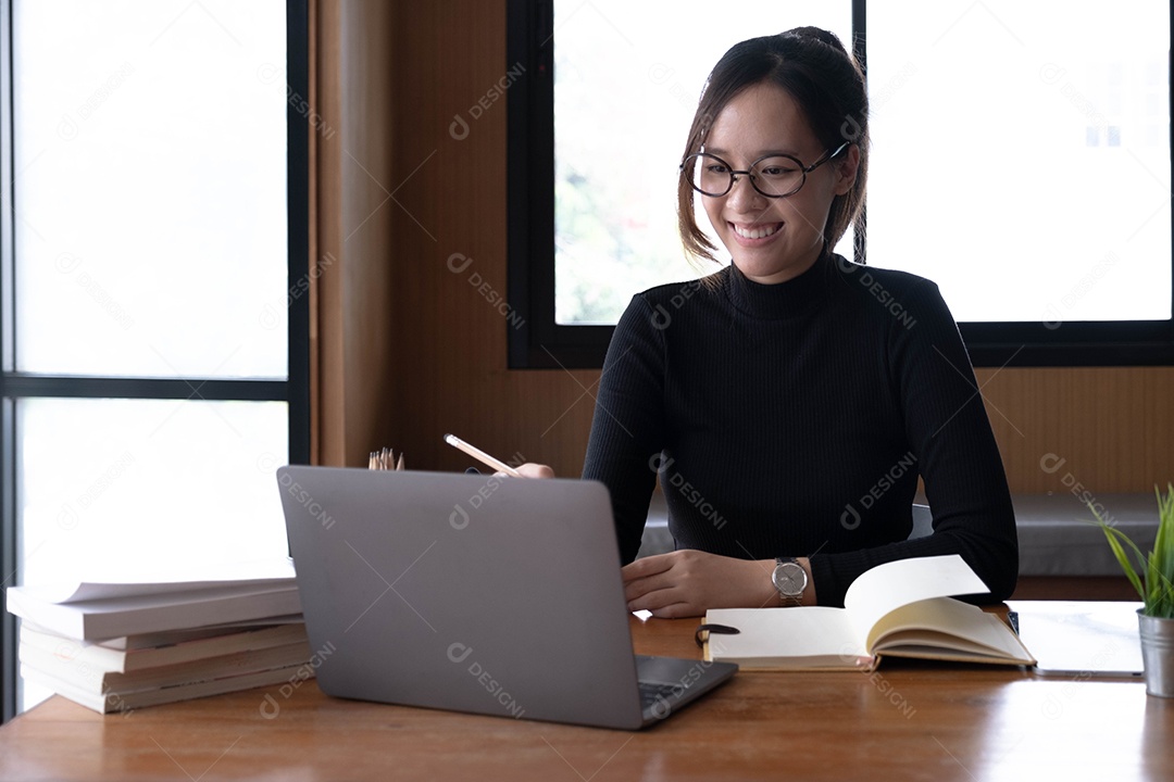 Encantadora mulher asiática trabalhando no escritório usando um laptop