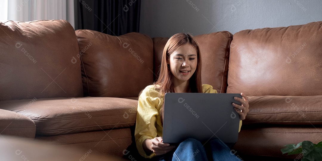 Bela jovem asiática usando laptop sentada no chão