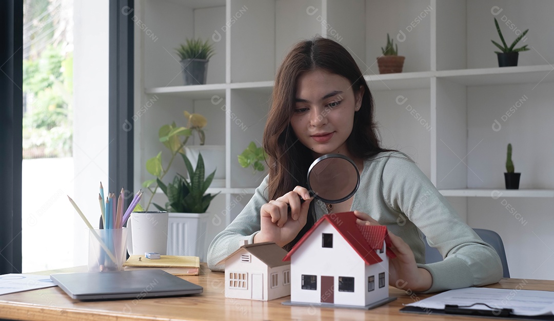 Mulher feliz segurando uma lupa e olhando para a casa