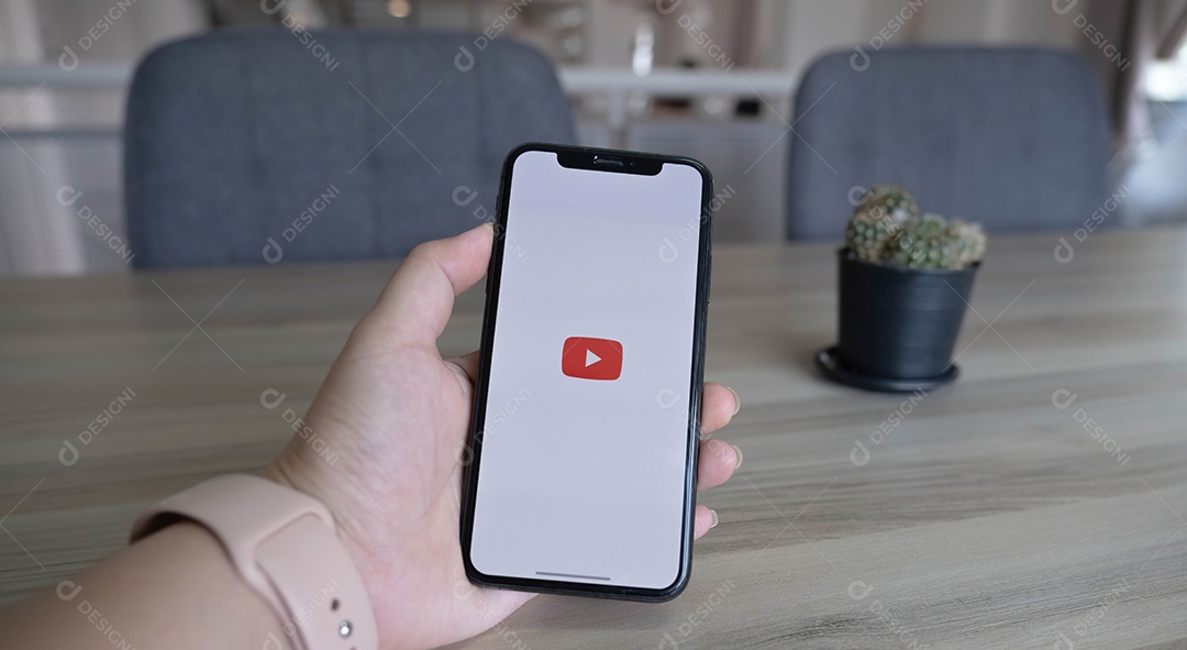 Mulher segurando um iPhone Xs ou iPhone 10 com o serviço social de Internet Youtube na tela