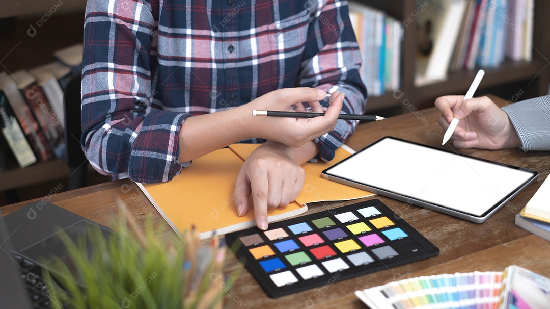 Dois artistas trabalhando em tablet, tom de papel colorido no espaço de trabalho