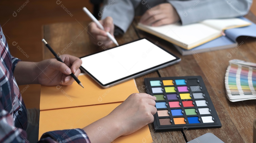 Dois artistas trabalhando em tablet, tom de papel colorido no espaço de trabalho