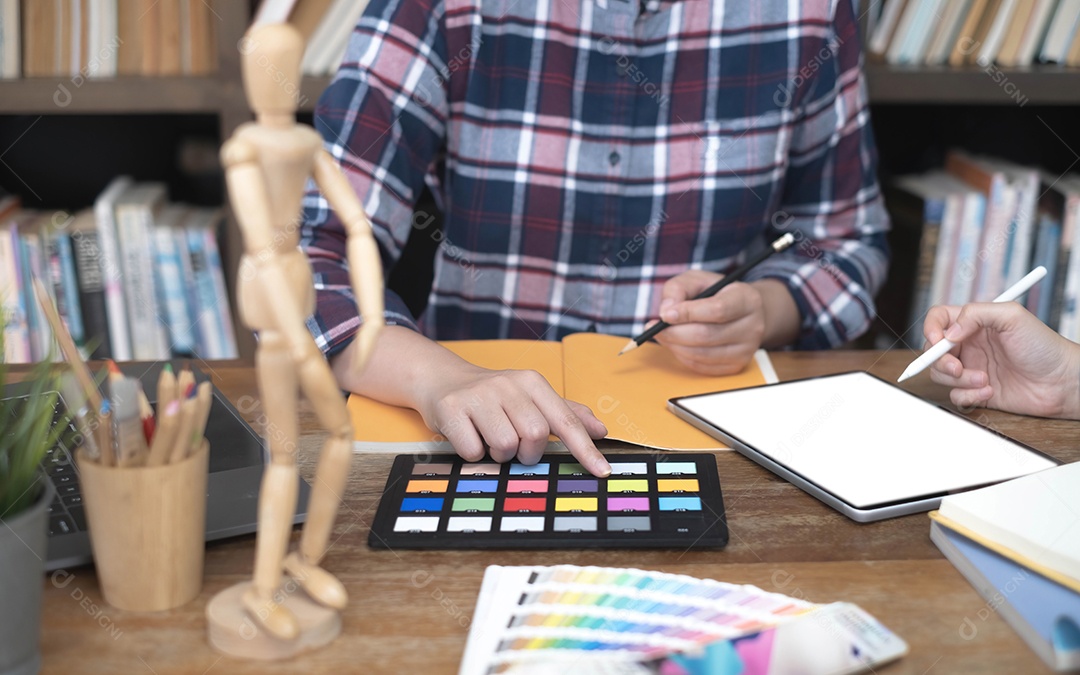 Dois artistas trabalhando em tablet, tom de papel colorido no espaço de trabalho