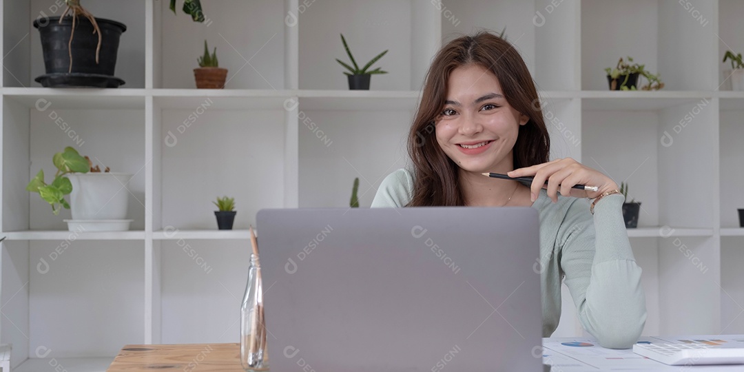 Encantadora mulher asiática trabalhando no escritório usando um laptop