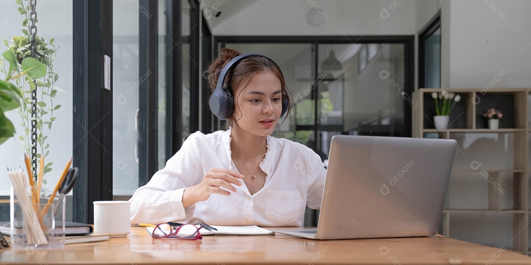 Feliz jovem adolescente asiática olhando para a tela acenando com a mão videochamada